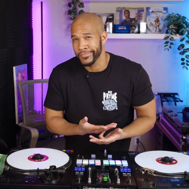 deejaypryme in the studio behind his turntables, explaining DJ technique on camera