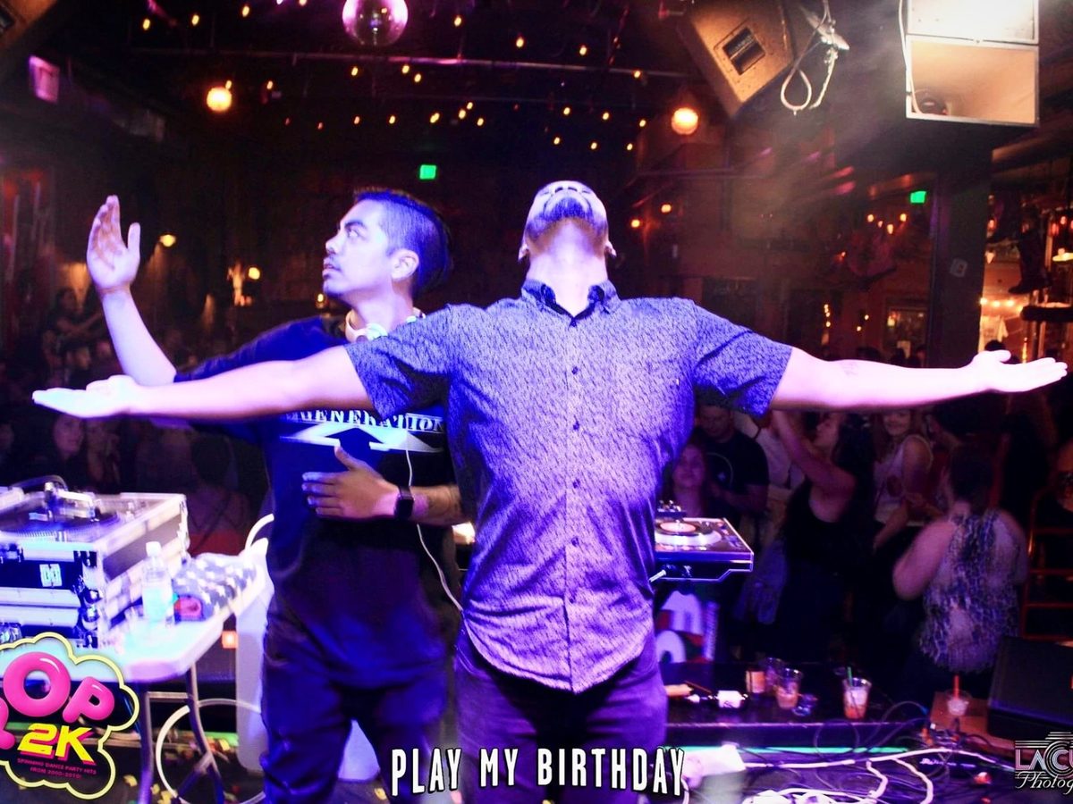 deejaypryme with arms outstretched on stage as the crowd reacts
