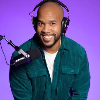 deejaypryme behind the decks with headphones and a Shure mic on a purple studio backdrop